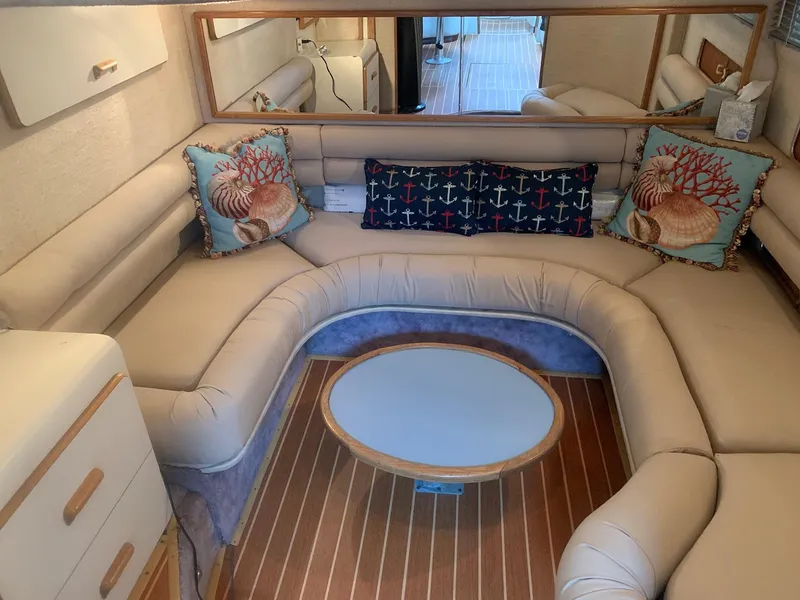 Slide: The Image of 1993 Sea Ray 440 Sundancer interior with U-shaped seating and nautical-themed pillows. - 29