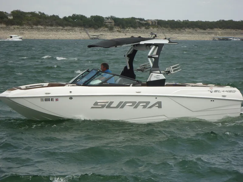 Slide: The Image of 2018 Supra SL boat cruising on a lake with a canopy and wakeboard tower. - 10