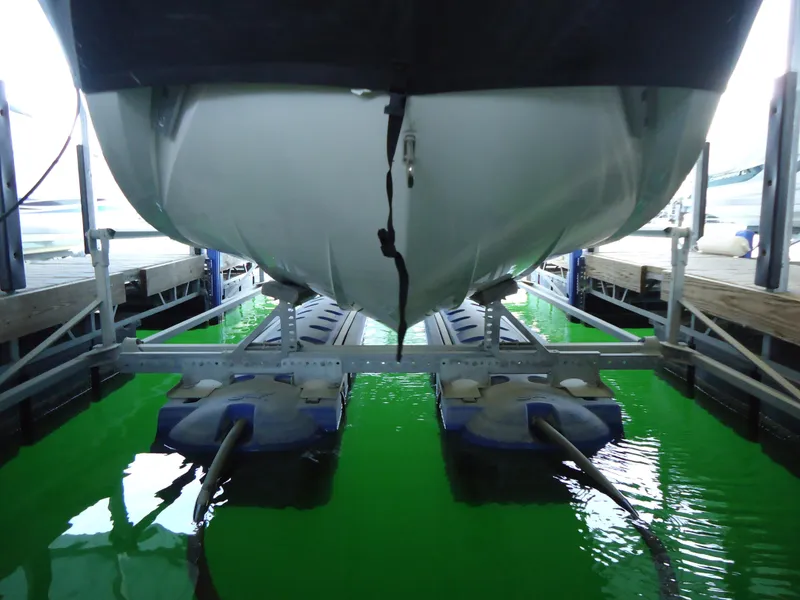 Slide: The Image of 2018 Supra SL boat on a lift in a marina with green water. - 12