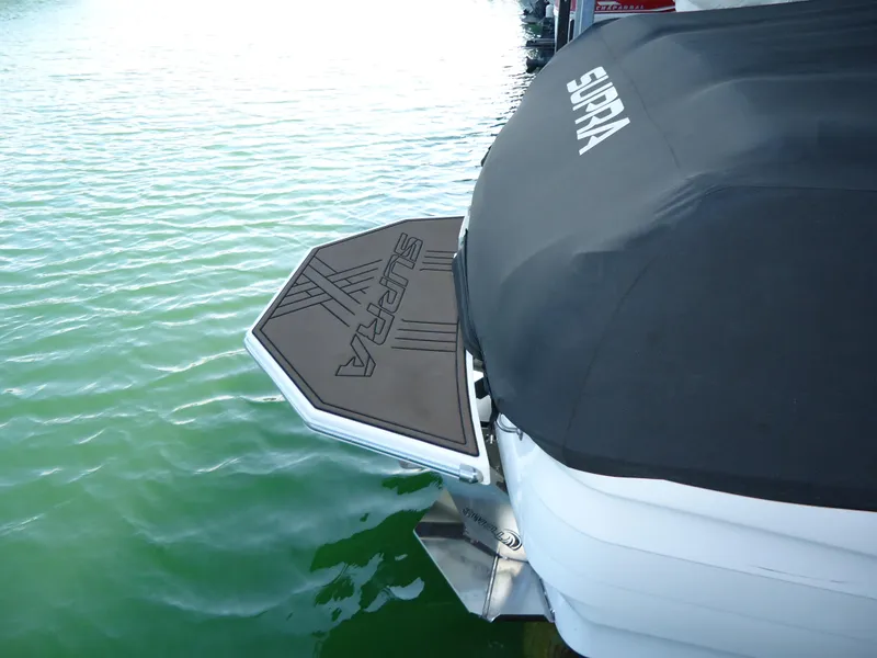 Slide: The Image of 2018 Supra SL boat with cover and swim platform on water. - 13