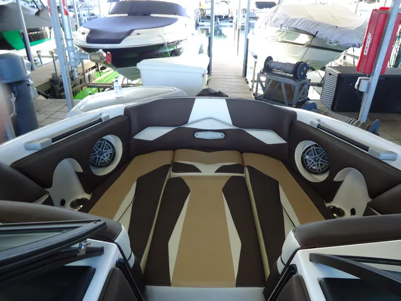 Slide: The Image of 2018 Supra SL boat interior with brown and white seating, docked among other boats. - 16