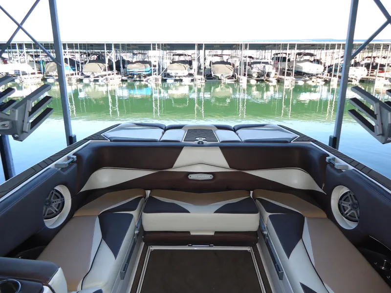 Slide: The Image of 2018 Supra SL boat interior with cushioned seating at a marina. - 19