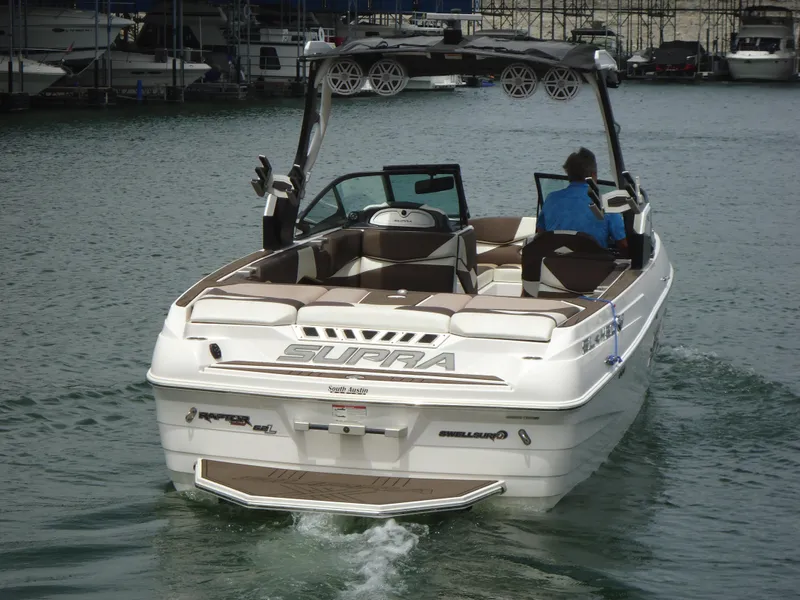 Slide: The Image of 2018 Supra SL boat cruising on water, rear view. - 2