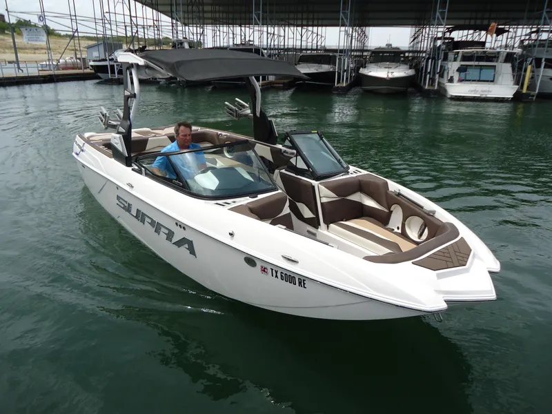 Slide: The Image of 2018 Supra SL boat docked in marina with canopy and seating. - 6