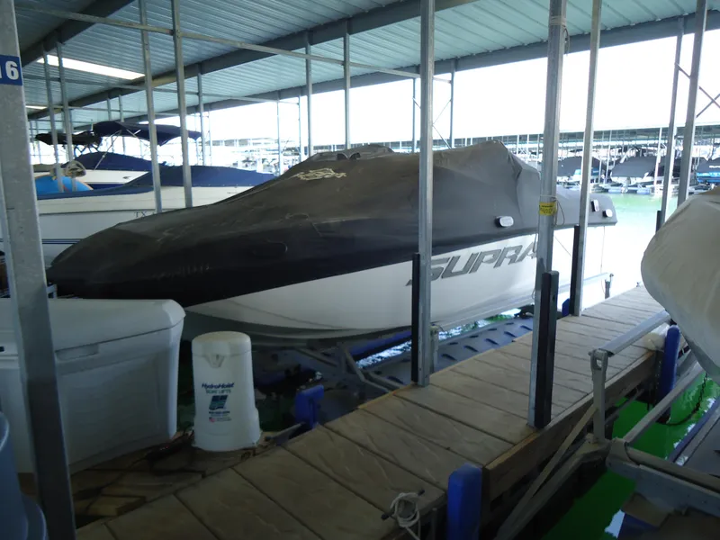 Slide: The Image of 2018 Supra SL boat covered and docked in a marina. - 8
