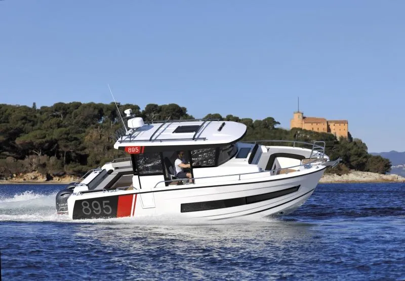 The Image of 2024 Jeanneau NC 895 Sport boat cruising on a scenic waterway. - 0