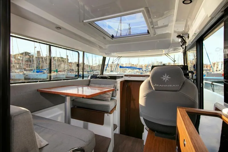 Slide: The Image of 2024 Jeanneau NC 895 Sport interior with seating, table, and helm station. - 13