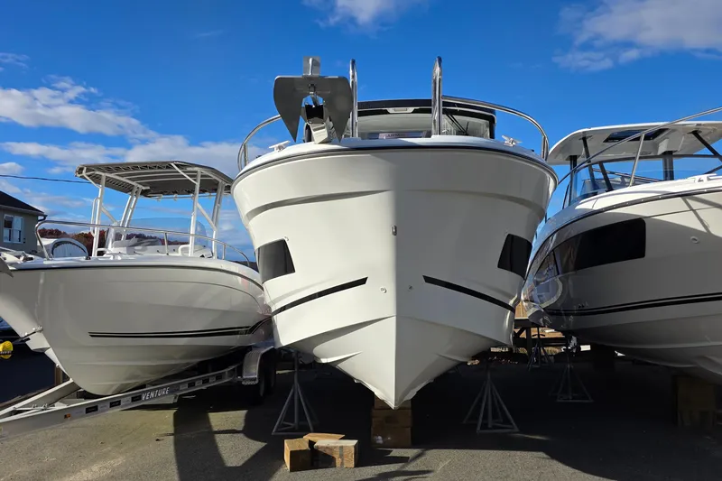 Slide: The Image of 2024 Jeanneau NC 895 Sport boat displayed outdoors, flanked by two other boats. - 27