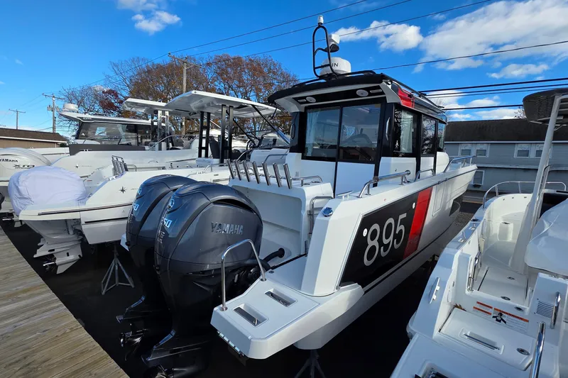 Slide: The Image of 2024 Jeanneau NC 895 Sport boat with Yamaha engines, docked under a clear blue sky. - 29