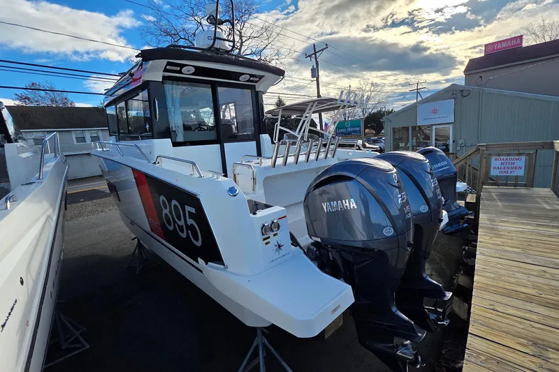 Slide: The Image of 2024 Jeanneau NC 895 Sport boat with Yamaha engines, displayed outdoors under a partly cloudy sky. - 30