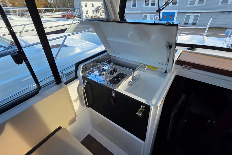 Slide: The Image of 2024 Jeanneau NC 895 Sport boat interior with compact kitchen and seating area. - 48