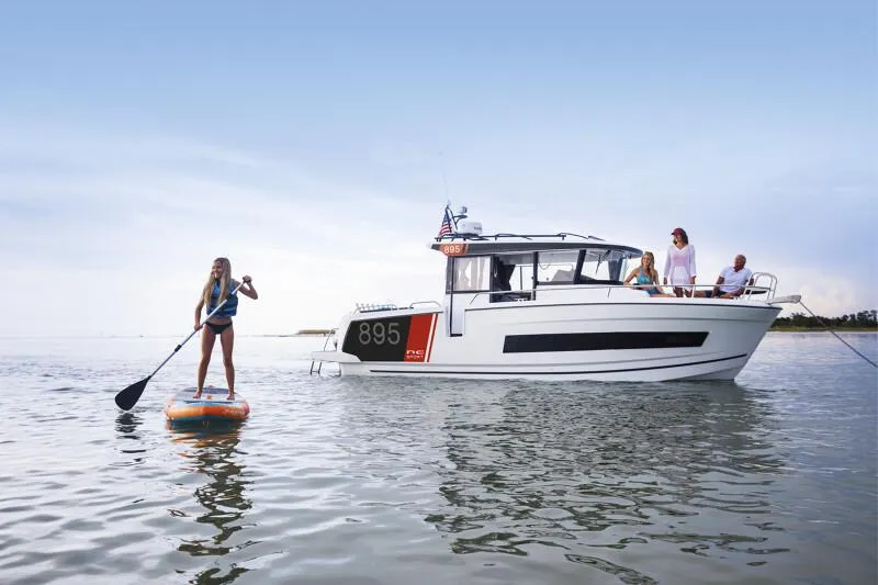 Slide: The Image of 2024 Jeanneau NC 895 Sport boat with people paddleboarding nearby. - 6