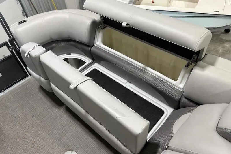 Slide: The Image of 2023 Regency 230 DL3 boat interior with open storage compartment and cushioned seating. - 11