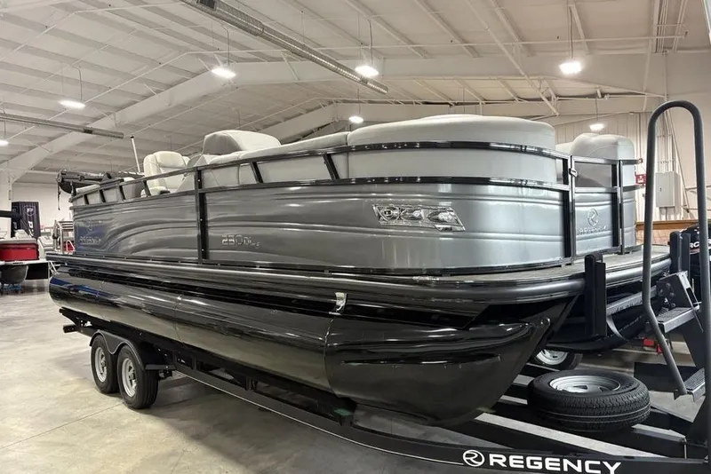 Slide: The Image of 2023 Regency 230 DL3 pontoon boat displayed indoors on a trailer. - 3