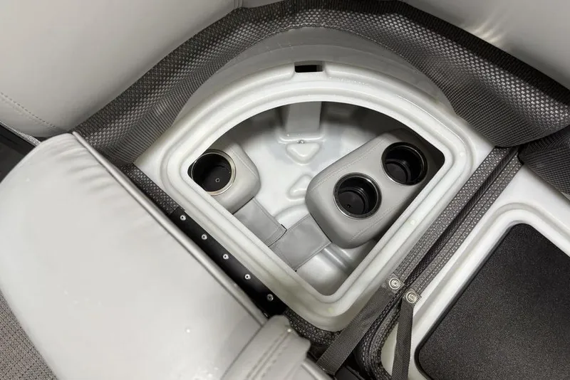 Slide: The Image of 2023 Regency 230 DL3 boat interior storage compartment with cup holders and cushioned seating. - 7