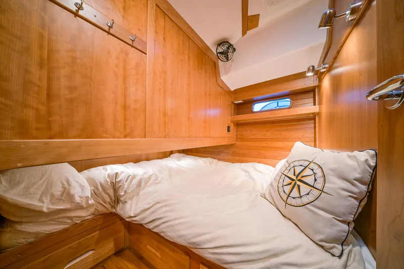 Slide: The Image of Cozy cabin interior of 2025 Tartan 455 sailboat with wooden finish and nautical-themed pillow. - 24