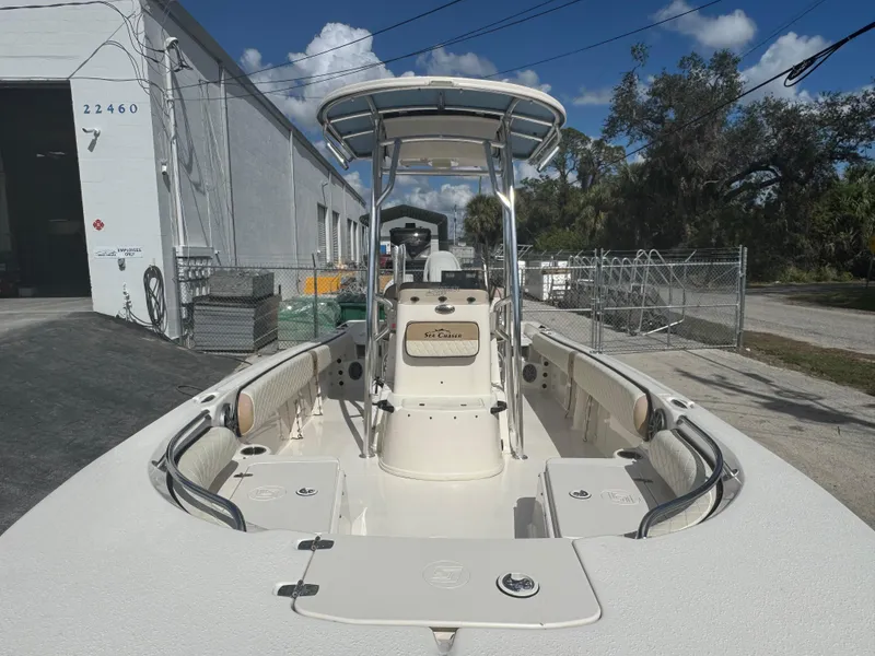 Slide: The Image of 2023 Carolina Skiff 21 Ultra Elite boat docked near a warehouse under a clear sky. - 16