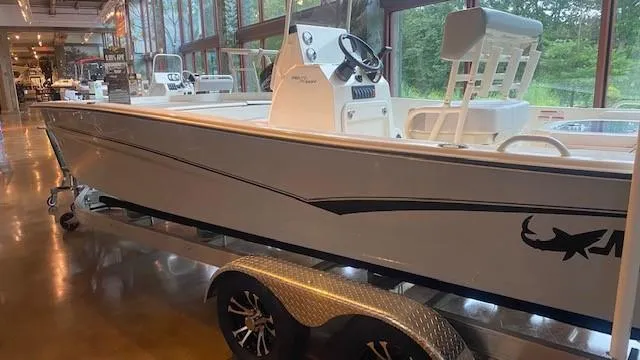 Slide: The Image of 2023 Mako Pro Skiff 19 CC boat on a trailer in a showroom. - 2