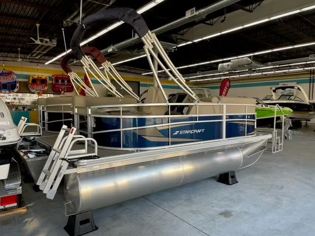 Slide: The Image of 2023 Starcraft LX 16 R pontoon boat displayed in a showroom. - 2