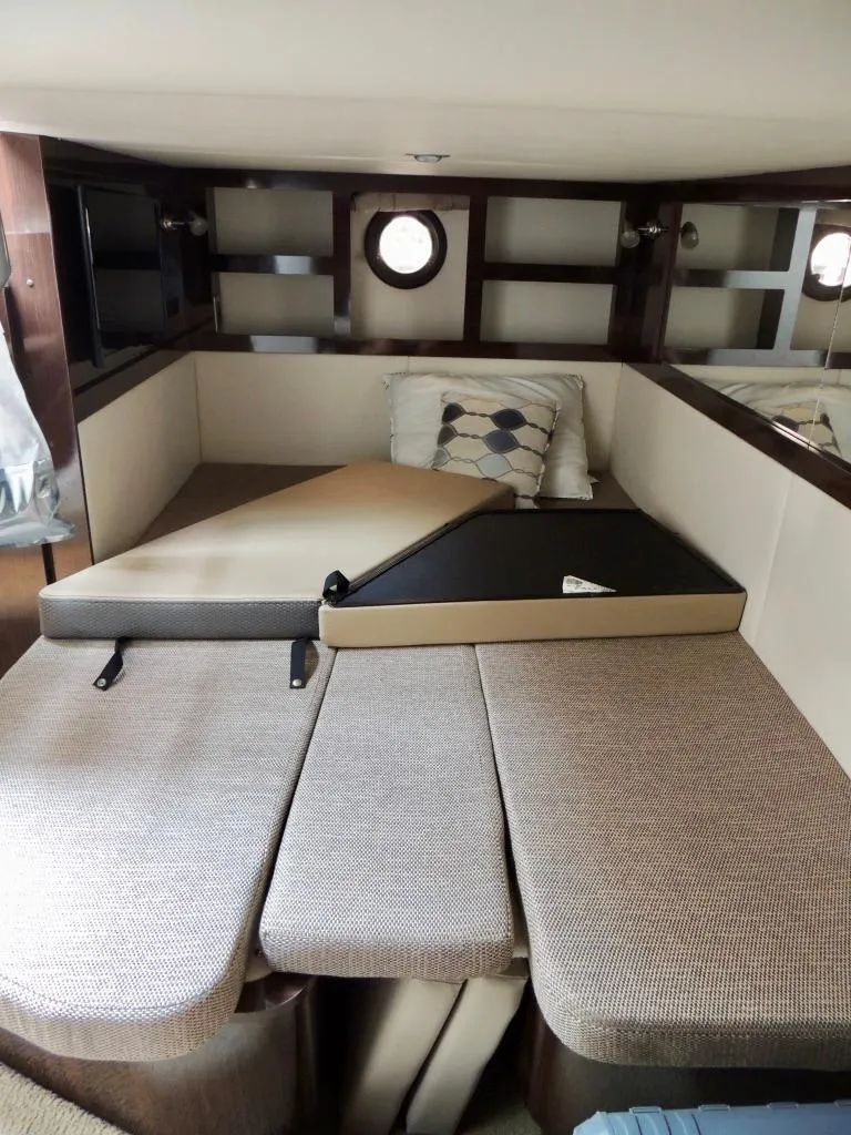 Slide: The Image of 2016 Sea Ray 350 Sundancer cabin interior with convertible seating and porthole windows. - 48