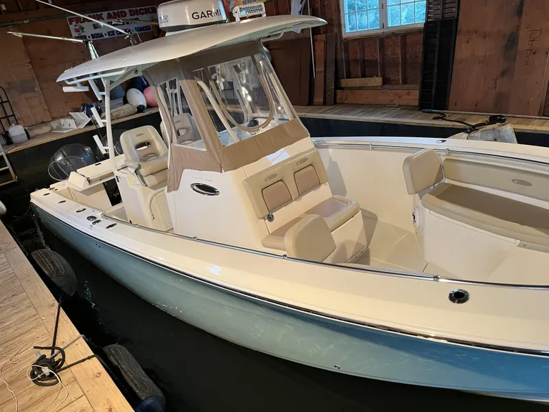 The Image of 2016 Cobia 296 CC boat docked indoors with beige seating and Garmin electronics. - 1