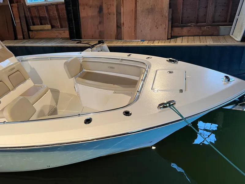 Slide: The Image of 2016 Cobia 296 CC boat docked indoors, showcasing bow seating and storage. - 4