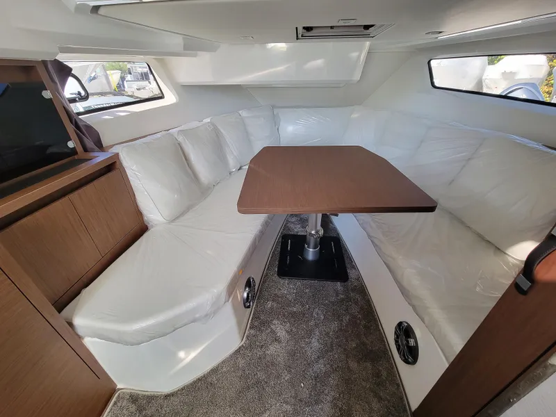 Slide: The Image of 2024 Jeanneau Leader 12.5 WA cabin with white seating and wooden table. - 40