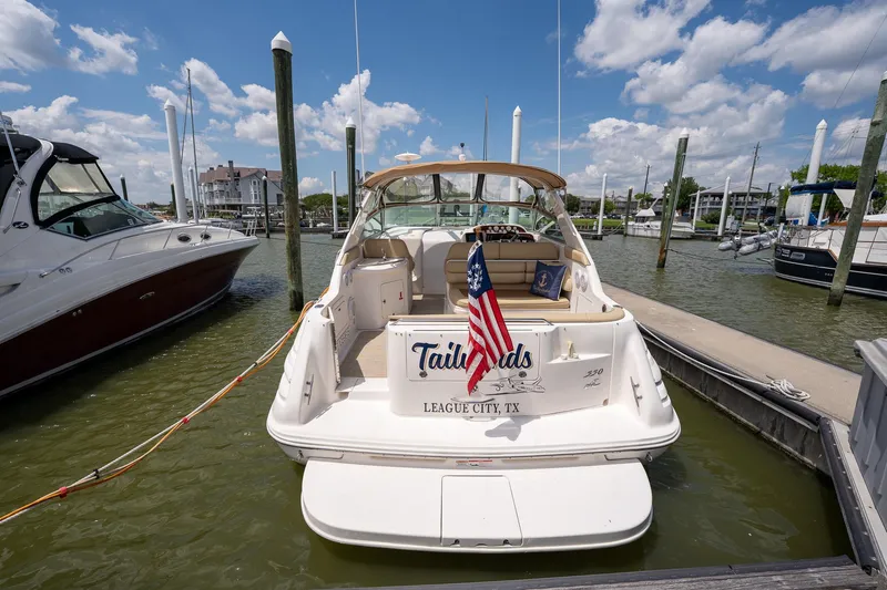 Slide: The Image of 1997 Sea Ray 330 Sundancer docked, displaying an American flag, under a partly cloudy sky. - 10
