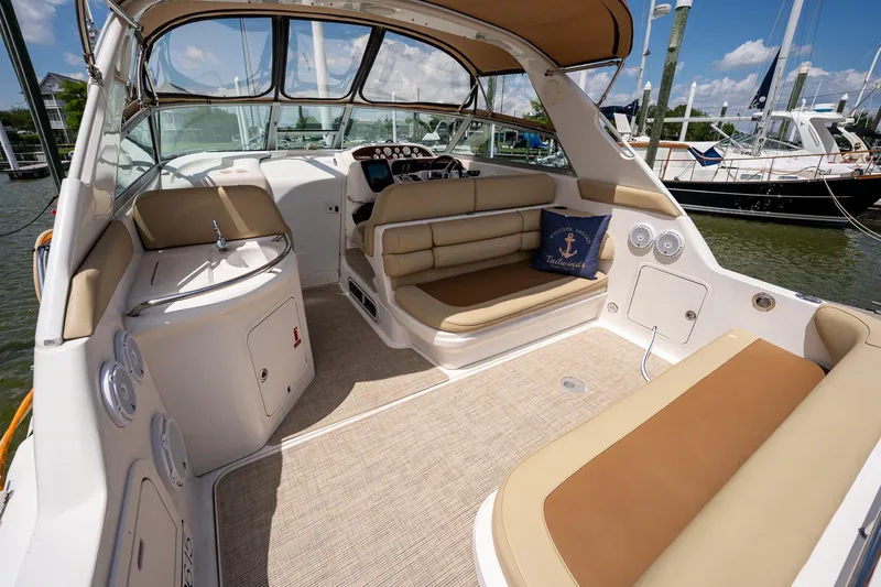 Slide: The Image of 1997 Sea Ray 330 Sundancer boat interior with beige seating and helm, docked at marina. - 12