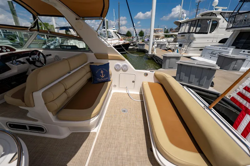 Slide: The Image of 1997 Sea Ray 330 Sundancer interior with beige seating, docked at marina under blue sky. - 13