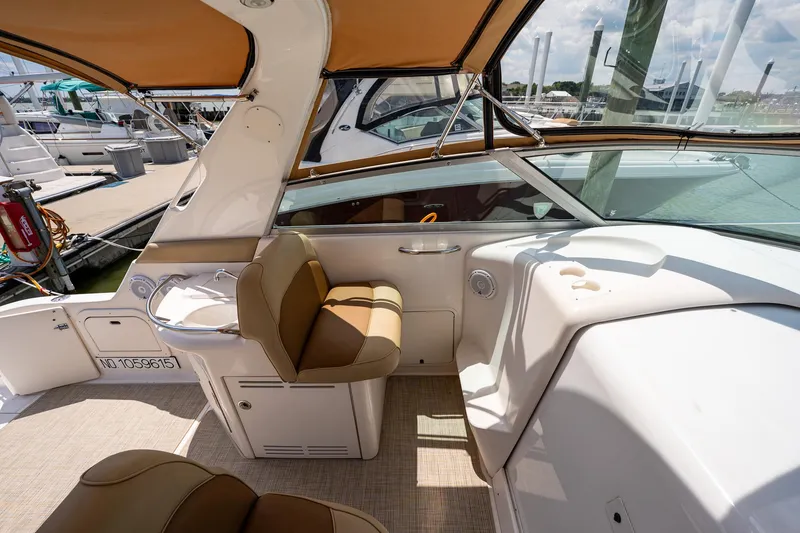Slide: The Image of 1997 Sea Ray 330 Sundancer cockpit with tan seating and helm, docked at marina. - 16