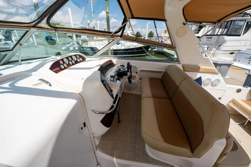 Slide: The Image of 1997 Sea Ray 330 Sundancer cockpit with tan seating and modern controls at marina. - 17