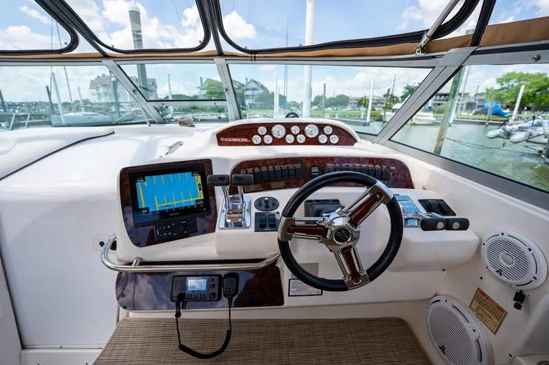 Slide: The Image of 1997 Sea Ray 330 Sundancer helm with navigation equipment and steering wheel, docked at marina. - 19