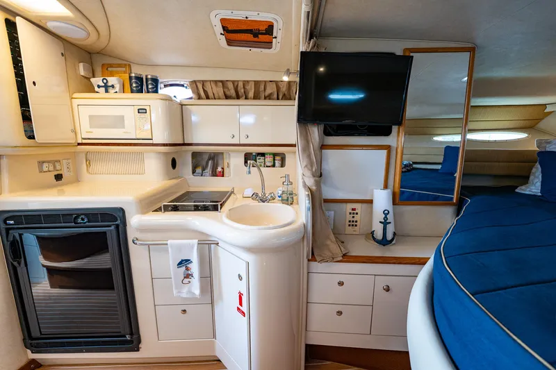 Slide: The Image of 1997 Sea Ray 330 Sundancer interior with kitchenette, sink, microwave, and cozy seating area. - 26