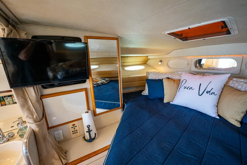 Slide: The Image of Interior of 1997 Sea Ray 330 Sundancer with cozy bed, TV, and nautical decor. - 29