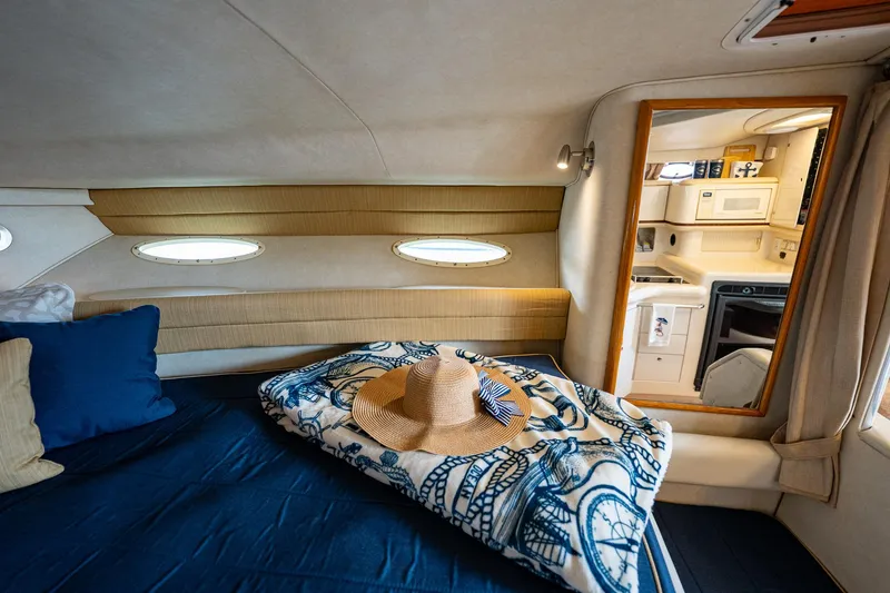 Slide: The Image of Cozy cabin interior of 1997 Sea Ray 330 Sundancer with bed, blanket, and hat. - 30