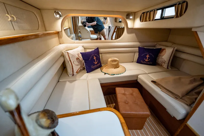 Slide: The Image of 1997 Sea Ray 330 Sundancer cabin with cozy seating, nautical pillows, and a straw hat. - 36