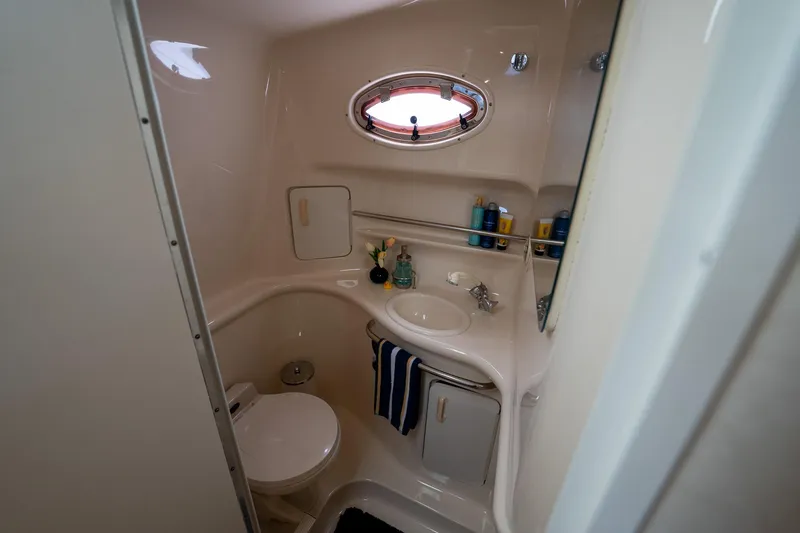 Slide: The Image of Bathroom interior of 1997 Sea Ray 330 Sundancer yacht, featuring sink, toilet, and porthole window. - 39