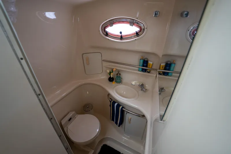 Slide: The Image of Bathroom interior of 1997 Sea Ray 330 Sundancer yacht, featuring sink, toilet, and porthole window. - 40