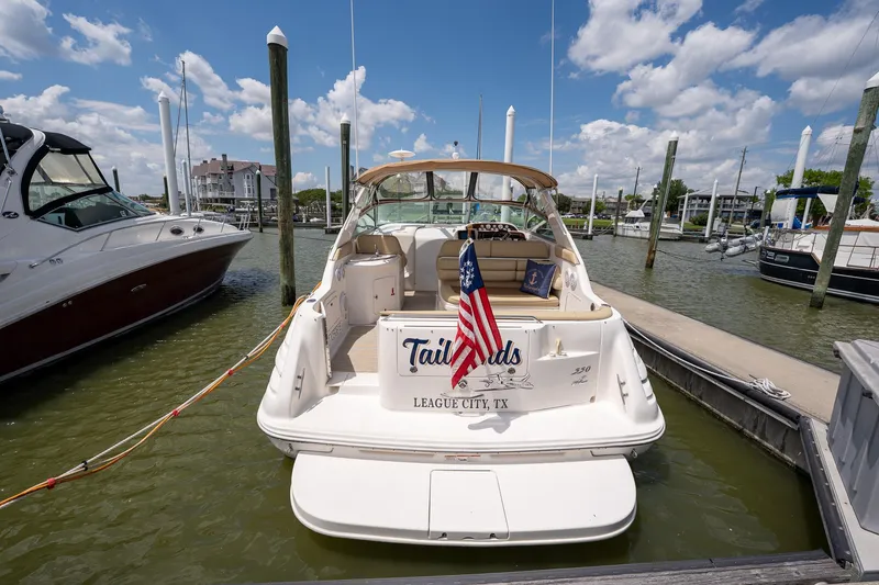 Slide: The Image of 1997 Sea Ray 330 Sundancer docked, displaying an American flag, under a partly cloudy sky. - 9