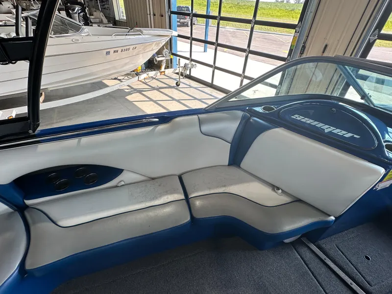 Slide: The Image of 2016 Sanger V215 boat interior with white and blue seating in a garage. - 16