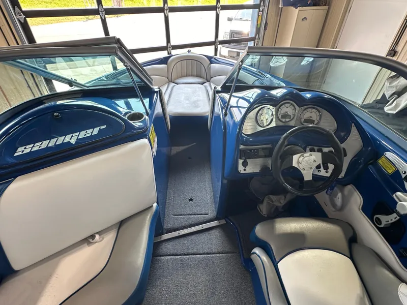 Slide: The Image of 2016 Sanger V215 boat interior with blue and white seating and dashboard. - 2