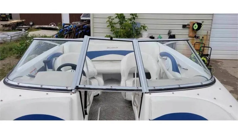Slide: The Image of 2008 Larson 180 Sport boat with white and blue interior, docked near a storage area. - 7