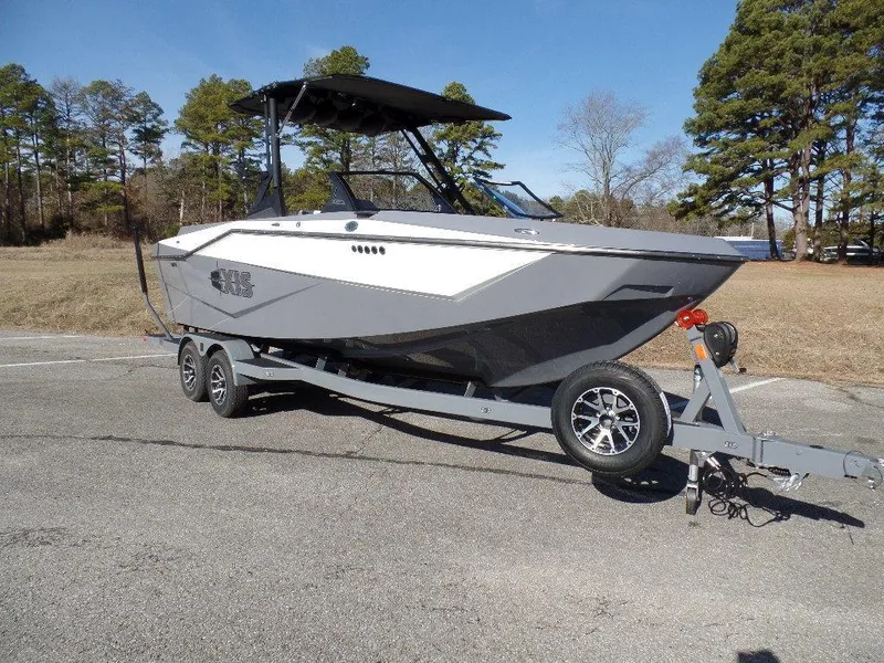 Slide: The Image of 2023 Axis T235 boat on trailer, parked outdoors, surrounded by trees. - 3