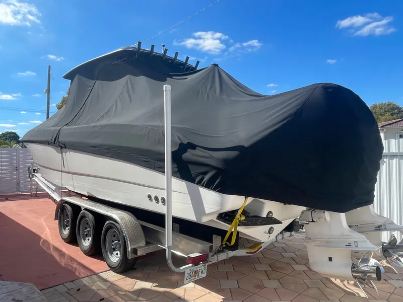 Slide: The Image of 2006 Wellcraft 310 CC boat on trailer with black cover, parked outdoors. - 11