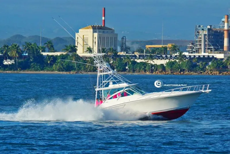 Slide: The Image of 2003 Cabo Express boat speeding on water near industrial shoreline. - 1