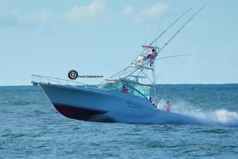 Slide: The Image of 2003 Cabo Express boat cruising on open sea with fishing rods. - 2