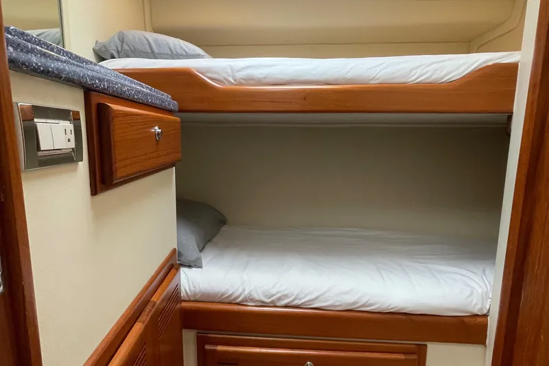 Slide: The Image of Bunk beds in 2003 Cabo Express yacht cabin with wooden accents and white bedding. - 4
