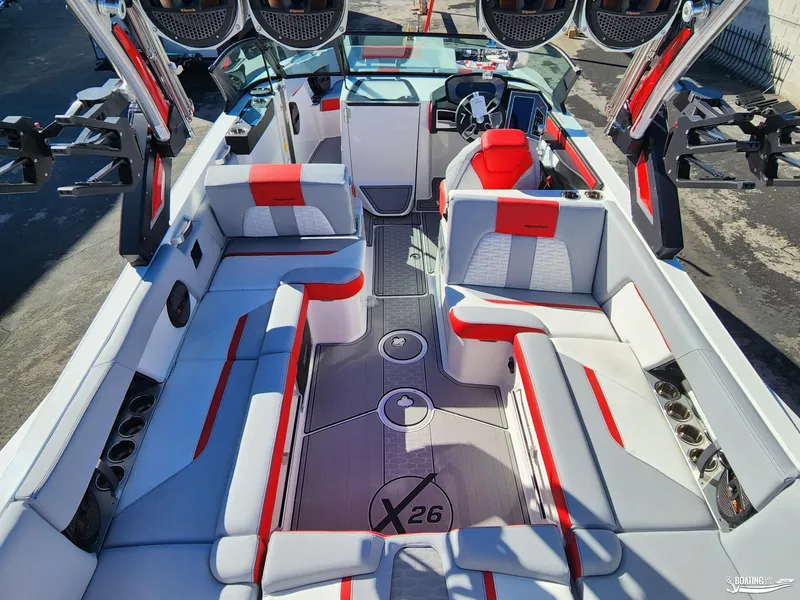 Slide: The Image of 2023 MasterCraft X26 boat interior with red and white seating, advanced dashboard, and spacious layout. - 12