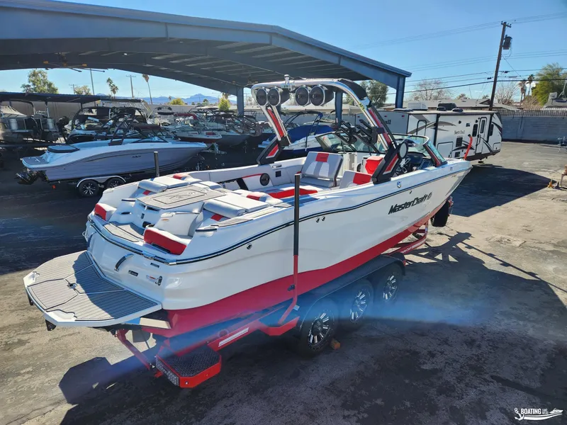 Slide: The Image of 2023 MasterCraft X26 boat in a showroom, featuring sleek design and vibrant red accents. - 2